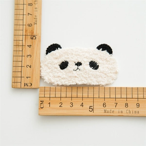 Close-up of white plush panda hair clip showing fuzzy texture and detailed embroidery