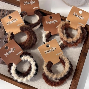 Gros plan d'élastiques à cheveux en peluche aux tons terre sur un plateau en bois rustique