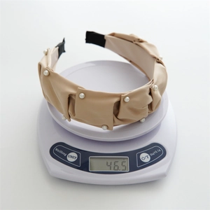 Close-up of beige pleated headband with white pearls on a scale weighing 46.5g