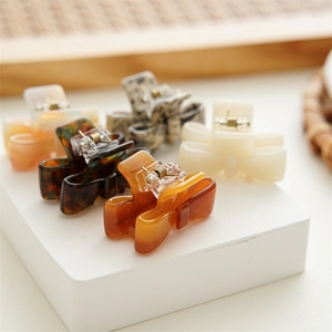 Detail view of five assorted acetate bow hair clips in amber and tortoiseshell patterns