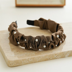 Detailed view of coffee satin pleated headband decorated with delicate white pearls