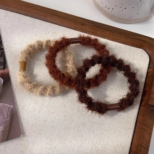 Détail de trois chouchous en peluche aux tons beige et marron disposés sur un plateau