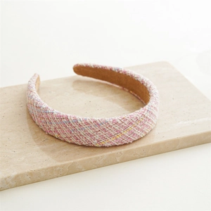 Detailed close-up of pink tweed headband with multicolor weaving on marble base