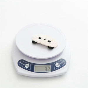 Detail shot of a white plush animal hair clip on a digital scale showing 3.2g weight