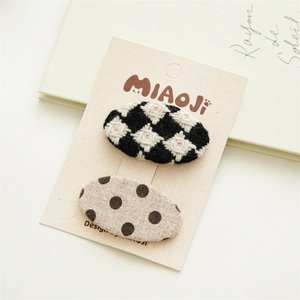 Détail de deux barrettes à cheveux en tissu à carreaux et pois sur carte d'emballage