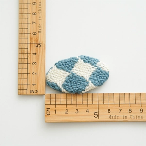 Vue de dessus détaillée d'une barrette en tricot à losanges bleus et blancs avec échelle