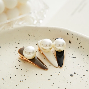 Detailed view of three pearl hair clips in brown, cream, and black on a ceramic tray