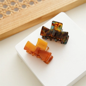 French retro acetate bow hair claws in tortoise shell and amber colors on rattan tray