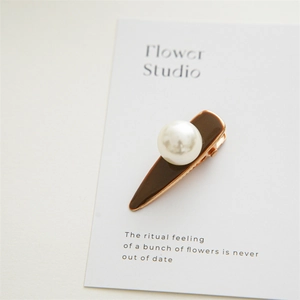 Detailed macro view of a brown glaze hair clip featuring a large pearl and rose gold alloy