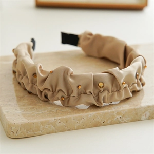 Close-up of pleated satin headband in coffee brown with amber crystal embellishments