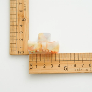 Small acetate bow hair claw clip with colorful marble pattern measuring 5cm in length