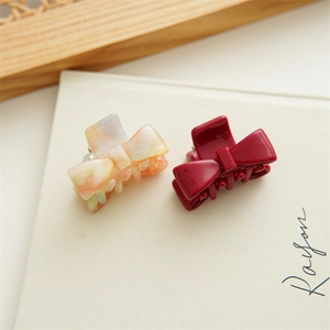 Close-up of marble pattern and burgundy acetate bow hair claws on a white background