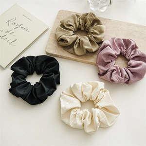 Flat lay of ribbed fabric scrunchies in black, cream, khaki, and dusty pink colors