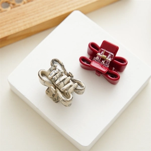 Close-up of small acetate bow hair claws in burgundy and marble beige finishes