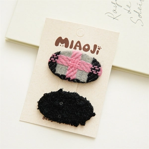 Détail de barrettes mignonnes en tissu avec motifs tissés gris et noirs texturés