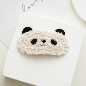 Close-up of cute plush panda hair clip with soft fleece texture on white display stand