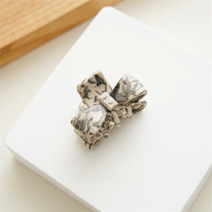 Detailed view of acetate bow hair claw clip with black and white marble pattern
