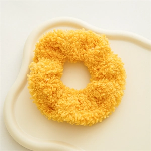 Λεπτομερής προβολή κίτρινου teddy fleece scrunchie σε διακοσμητικό κεραμικό δίσκο