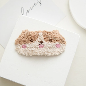 Close-up of cute plush dog face hair clip with soft embroidery details on white stone