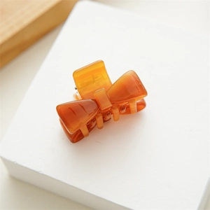 Close-up of small amber acetate bow hair claw clip with smooth polished finish