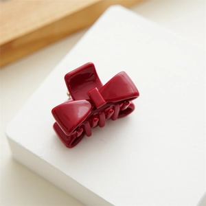 Macro shot of small burgundy acetate bow hair claw clip with glossy finish and metal spring