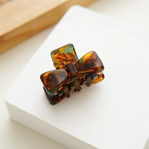 Detail of tortoise shell acetate bow hair claw clip with glossy finish on white stand
