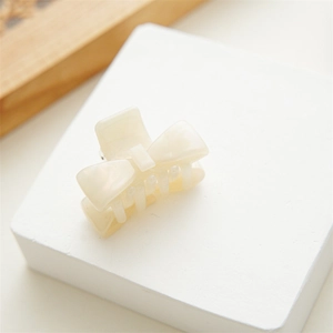 Detailed macro view of the cream-colored acetate bow hair claw clip with pearlescent finish