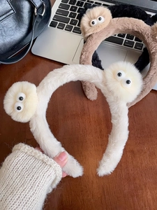 Vue détaillée des serre-têtes yeux de monstre en peluche blanche, marron et noire