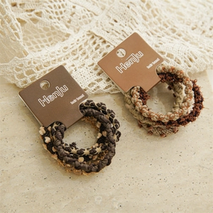 Brown braided elastic hair bands set on a display card with a scenic background