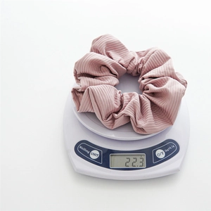 Detail shot showing the weight of a pink scrunchie on a scale at 22.3 grams