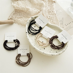 Detail of high-elasticity hair ties with gold beads on a ceramic tray with lace