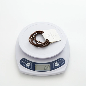 Brown elastic hair ties set with gold beads on a digital scale for weight display