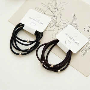 Close-up of minimalist high-elastic hair ties with small gold beads on a paper card