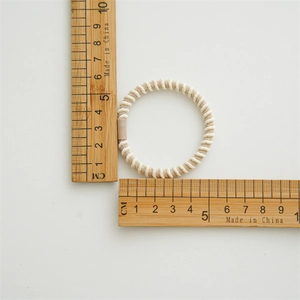 Detail view of a cream twist hair tie with a ruler showing its 5cm diameter size