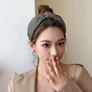 Classic black and white houndstooth knotted headband worn by a female model with high top