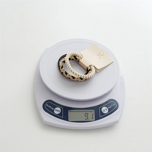 Macro shot showing 9.1g weight of brown braided hair ties on a digital scale