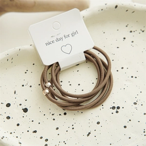 Detail of 5-piece minimalist elastic hair ties set with gold beads on white display card