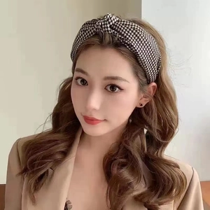 Front view of model wearing a vintage houndstooth knotted headband with brown curly hair