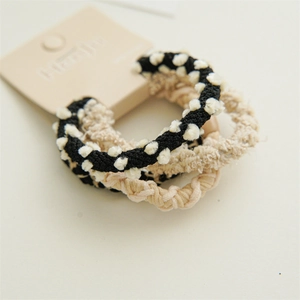 Macro detail of braided elastic hair ties in brown tones with soft pom-pom and plush texture