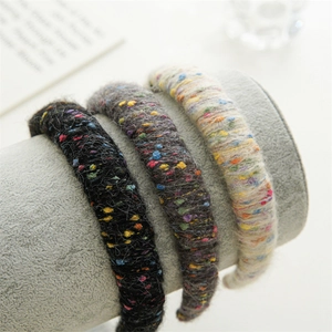 Vue détaillée de trois serre-têtes en tricot noir, gris et beige avec des points colorés