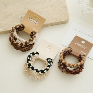 Detailed view of assorted coffee-toned braided hair ties on elegant packaging