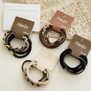 Close-up of brown braided elastic hair ties set on a vintage lace and card background