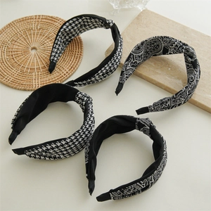Close-up of four knotted headbands in houndstooth and paisley patterns on marble
