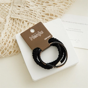 Detailed view of three black elastic hair ties with woven textures and check pattern accents