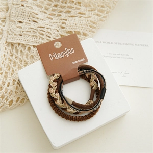 Close-up of brown braided hair ties and classic plaid scrunchie on a white display stand