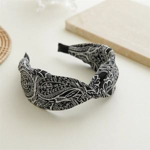 Detail of black and white paisley fabric headband with a stylish twisted knot design