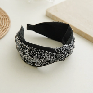 Detail of wide knotted headband with black and white paisley and floral patterns