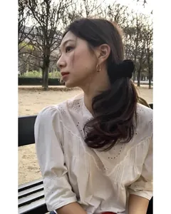 Detailed view of an elegant black velvet scrunchie worn in a French romantic garden setting