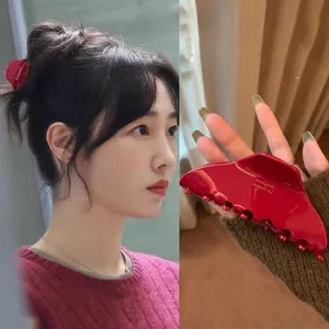 Détail d'une grande pince à cheveux en acétate rouge brillant avec étiquette dorée et dents