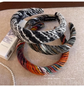 Detailed view of three thick knitted headbands in black, colorful, and orange yarn textures